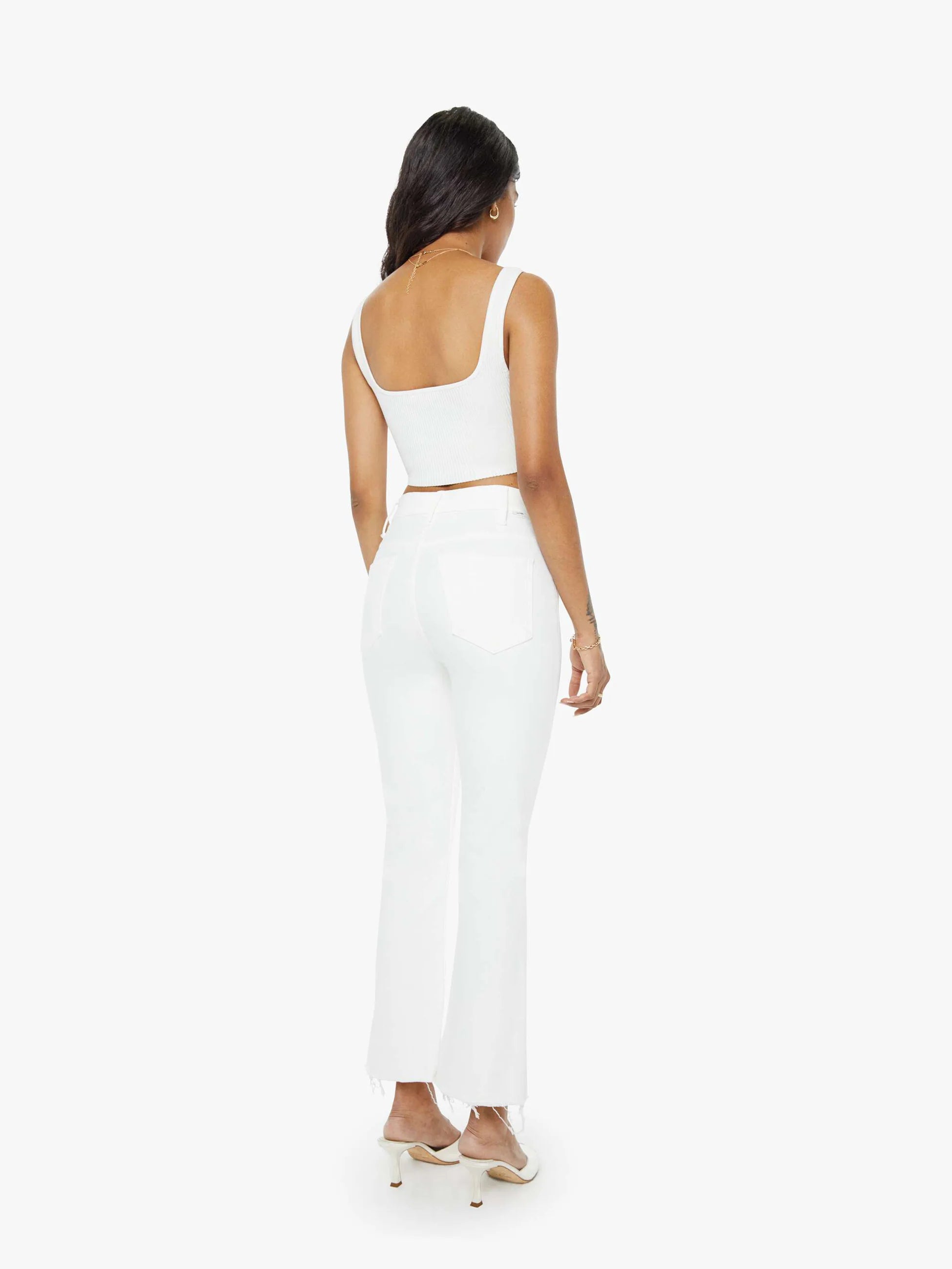 Woman wearing a white sleeveless top and high-waisted pants on a white background