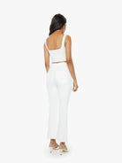 Woman wearing a white sleeveless top and high-waisted pants on a white background