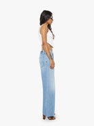 Woman wearing light blue jeans and a white top on a white background