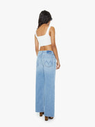 Woman wearing light blue jeans with a brand logo on a white background
