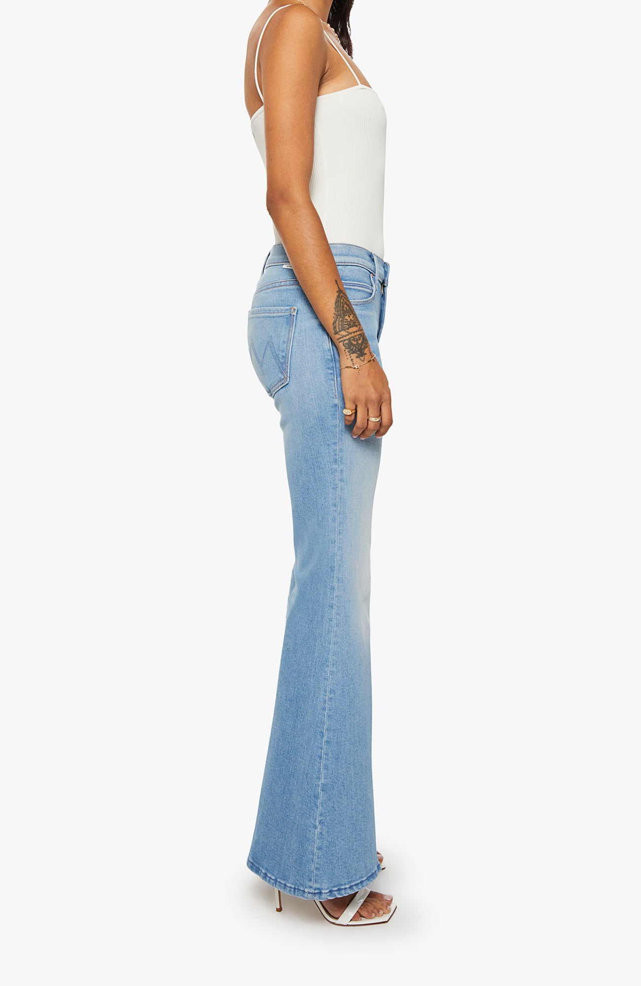 Woman wearing light blue flared jeans on a white background