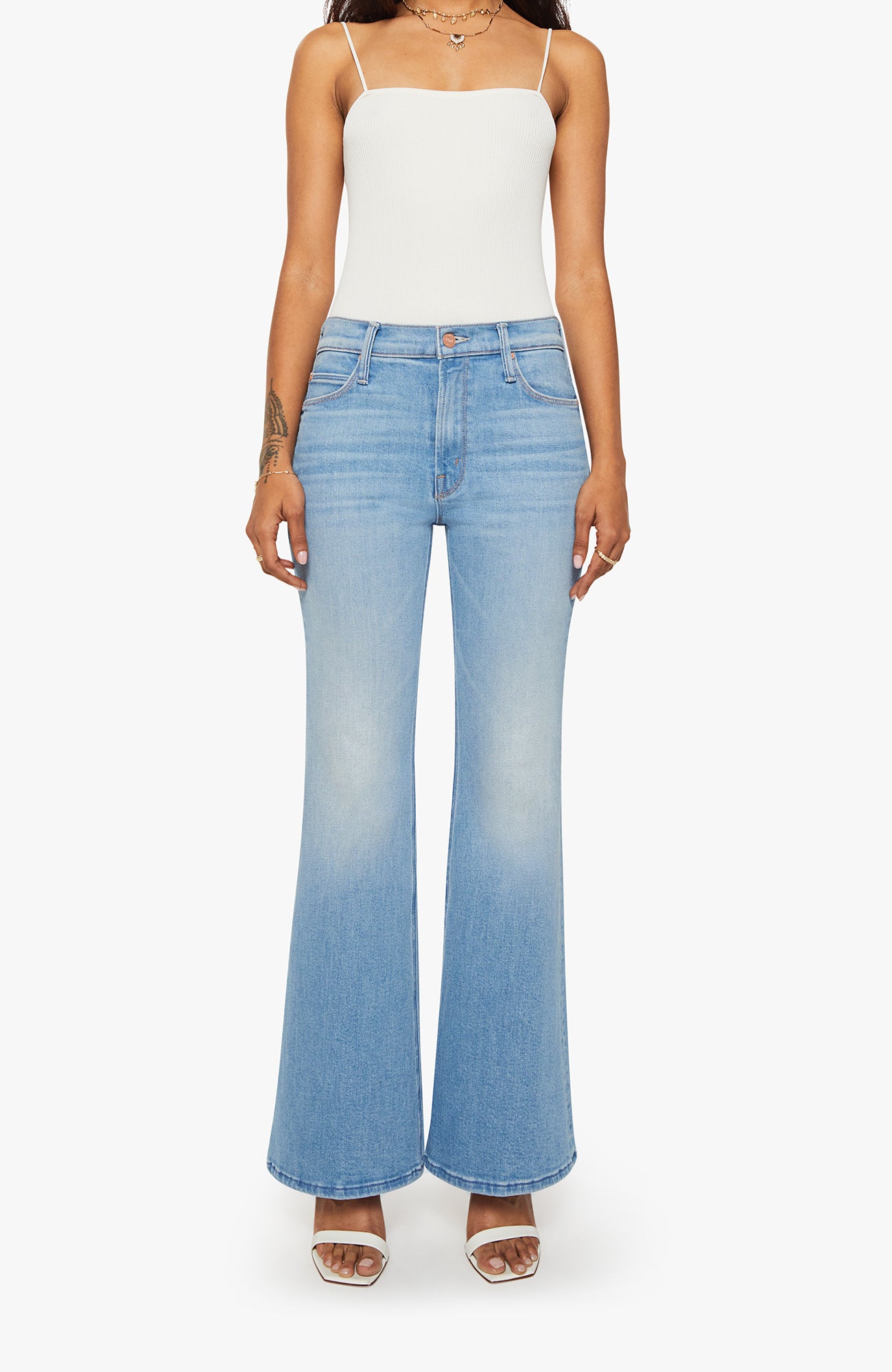 Person wearing a white top and blue flared jeans on a white background