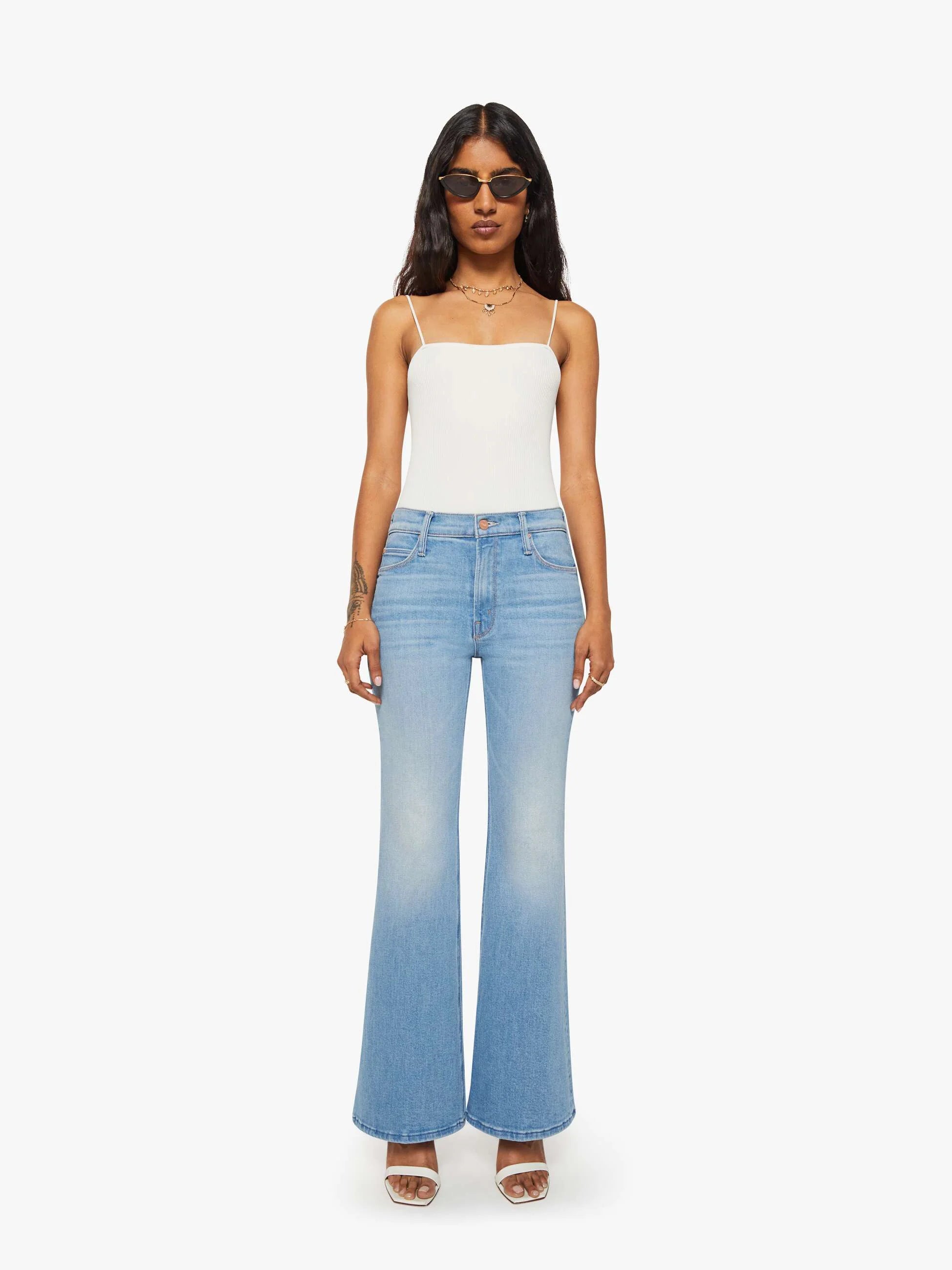 Woman wearing a white top and light blue jeans on a white background