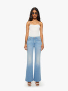Woman wearing a white top and light blue jeans on a white background