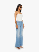 Woman wearing a white top and light blue jeans on a white background