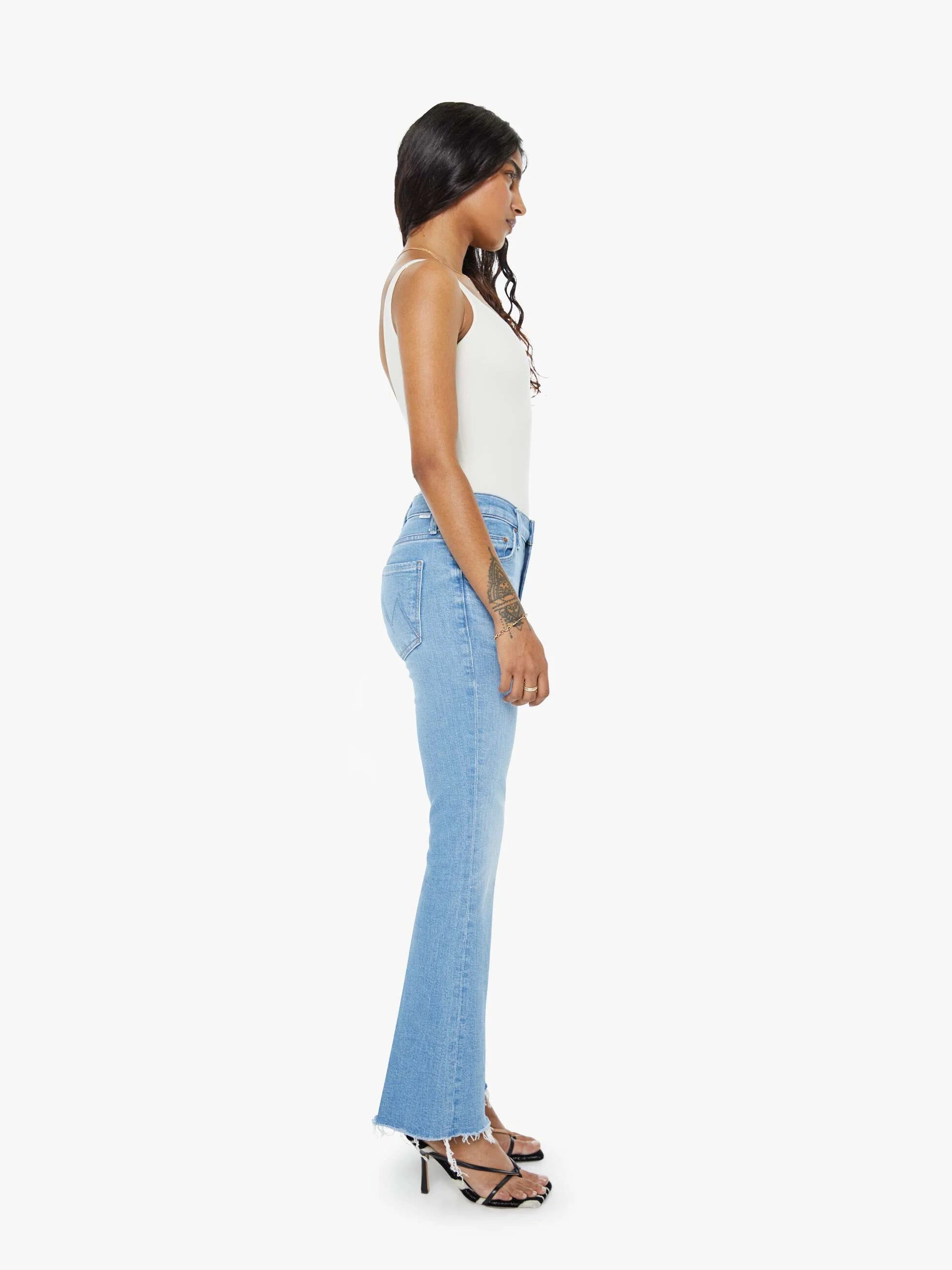 Woman wearing light blue flared jeans on a white background