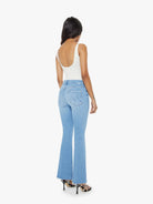 Woman wearing light blue jeans and a white top on a white background