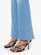 Black strappy high-heeled sandals worn with light blue jeans on a white background