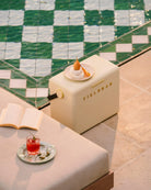 Beige refrigerator with 'FIELDBAR' branding on a tiled floor with a book and drink.