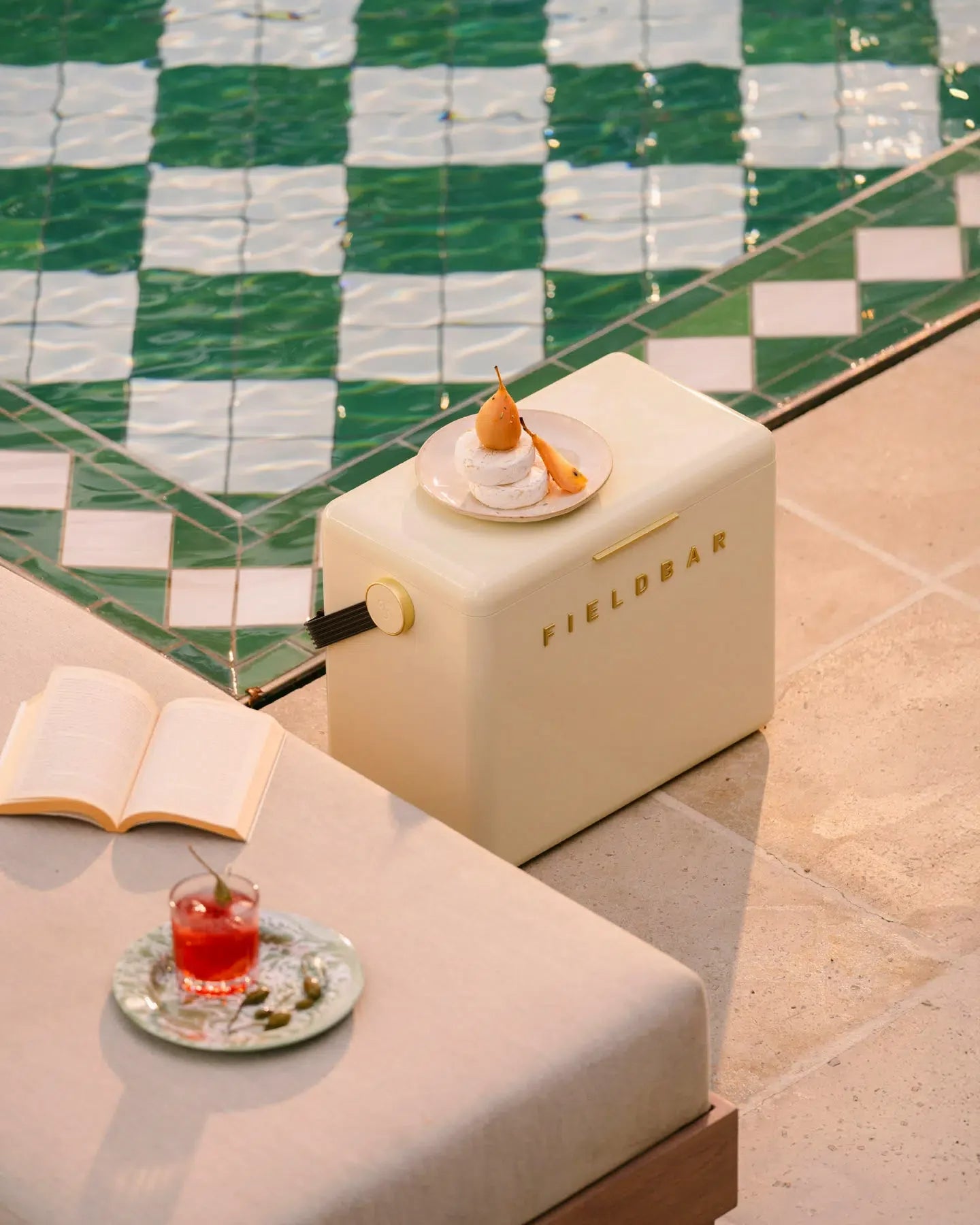 Beige refrigerator with 'FIELDBAR' branding on a tiled floor with a book and drink.