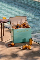 Teal cooler labeled 'FIELDBAR' filled with drinks by a poolside.