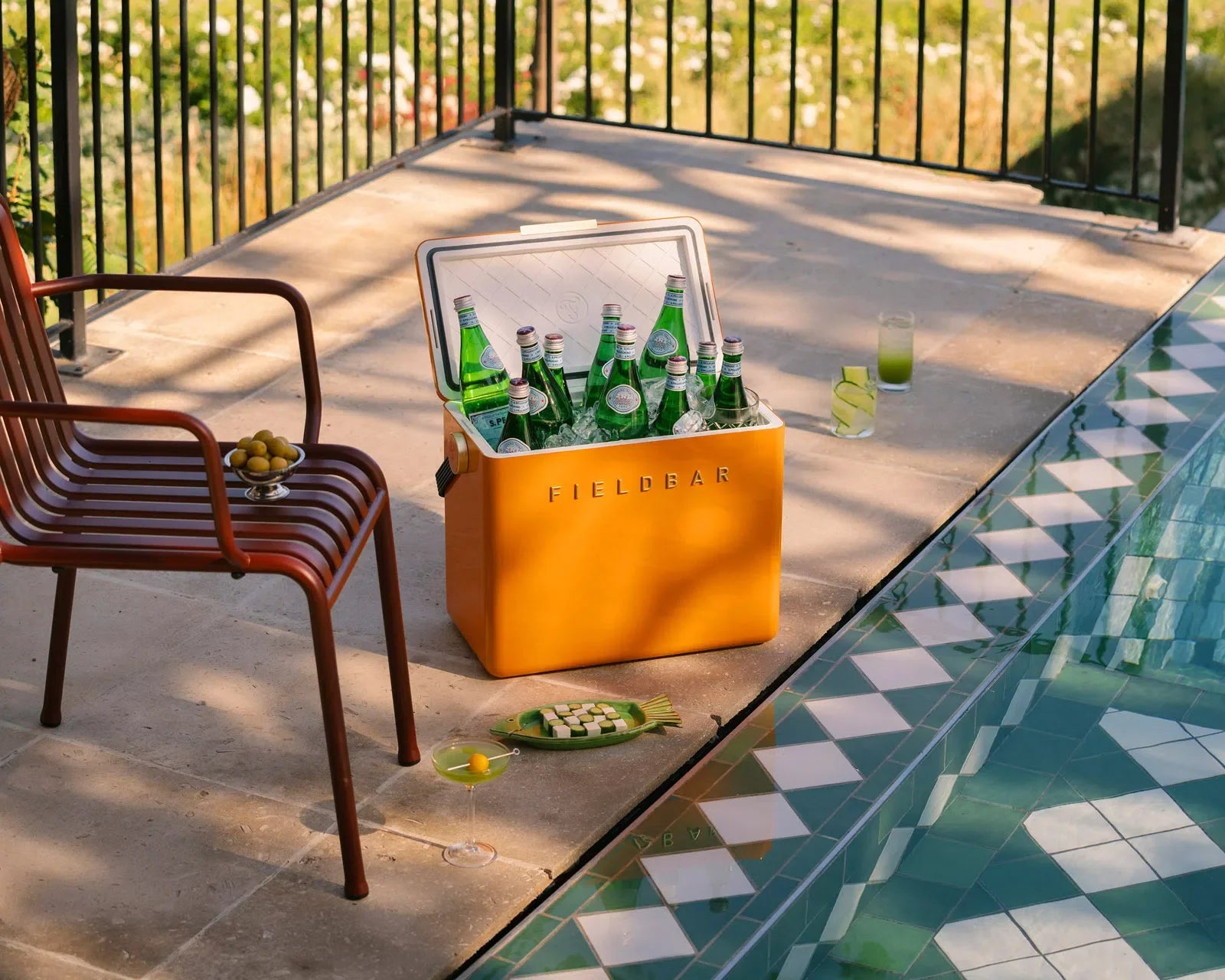 Orange cooler box with drinks by a poolside on a patio