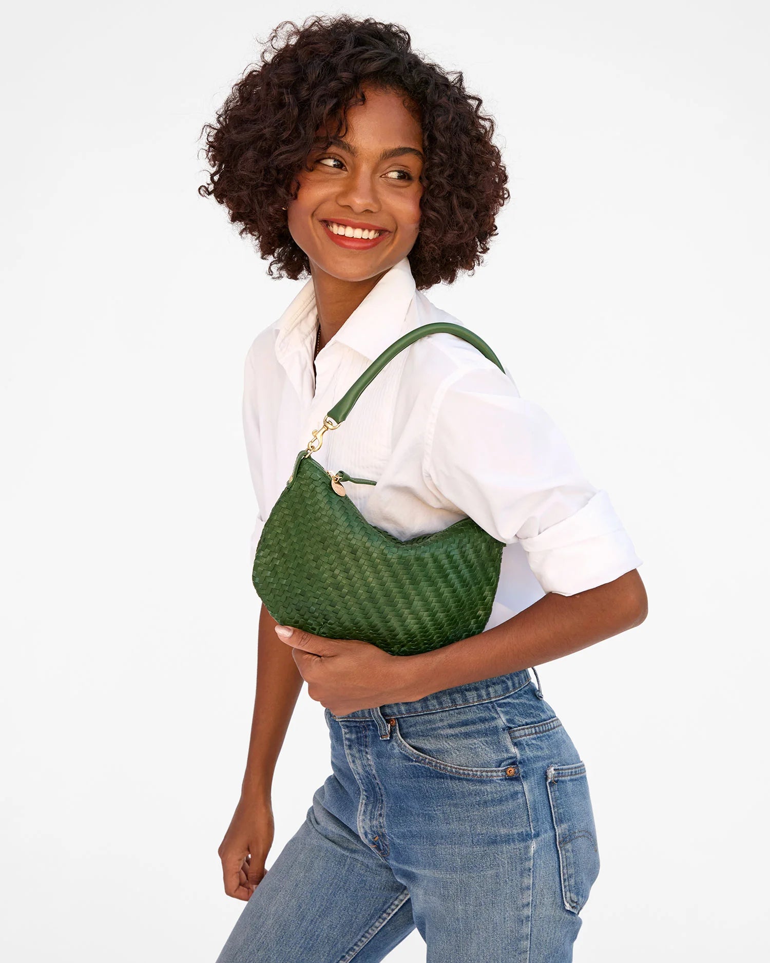Woman holding a green woven handbag against a white background
