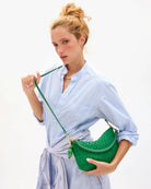 Woman holding a green handbag against a white background