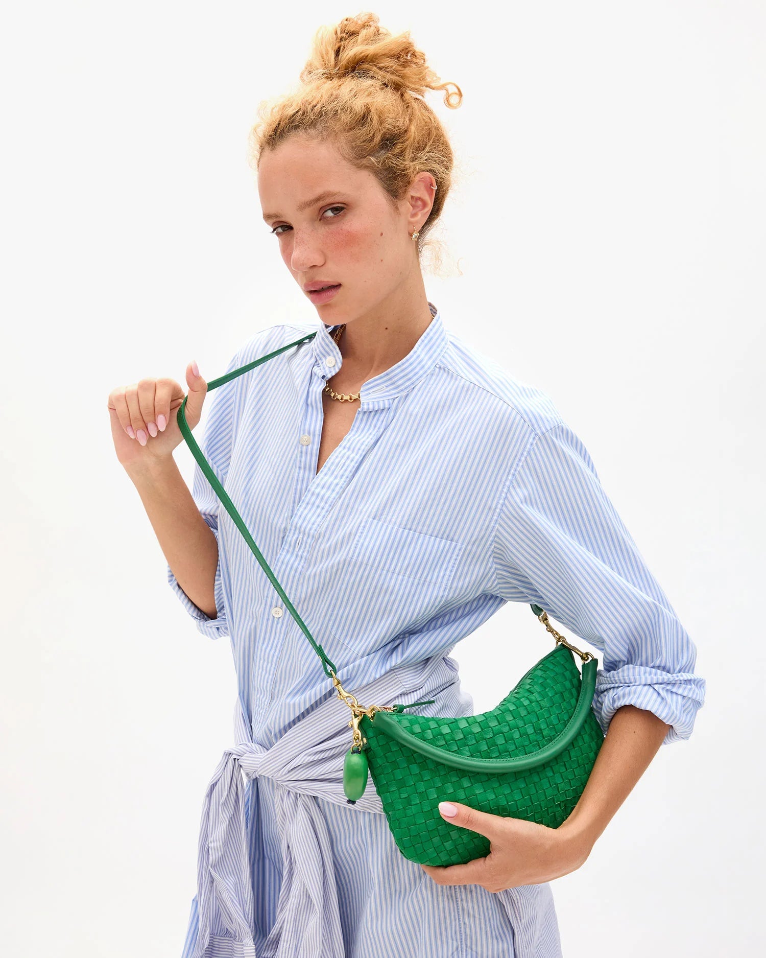 Woman holding a green handbag against a white background