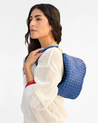 Woman wearing a blue woven backpack on a white background