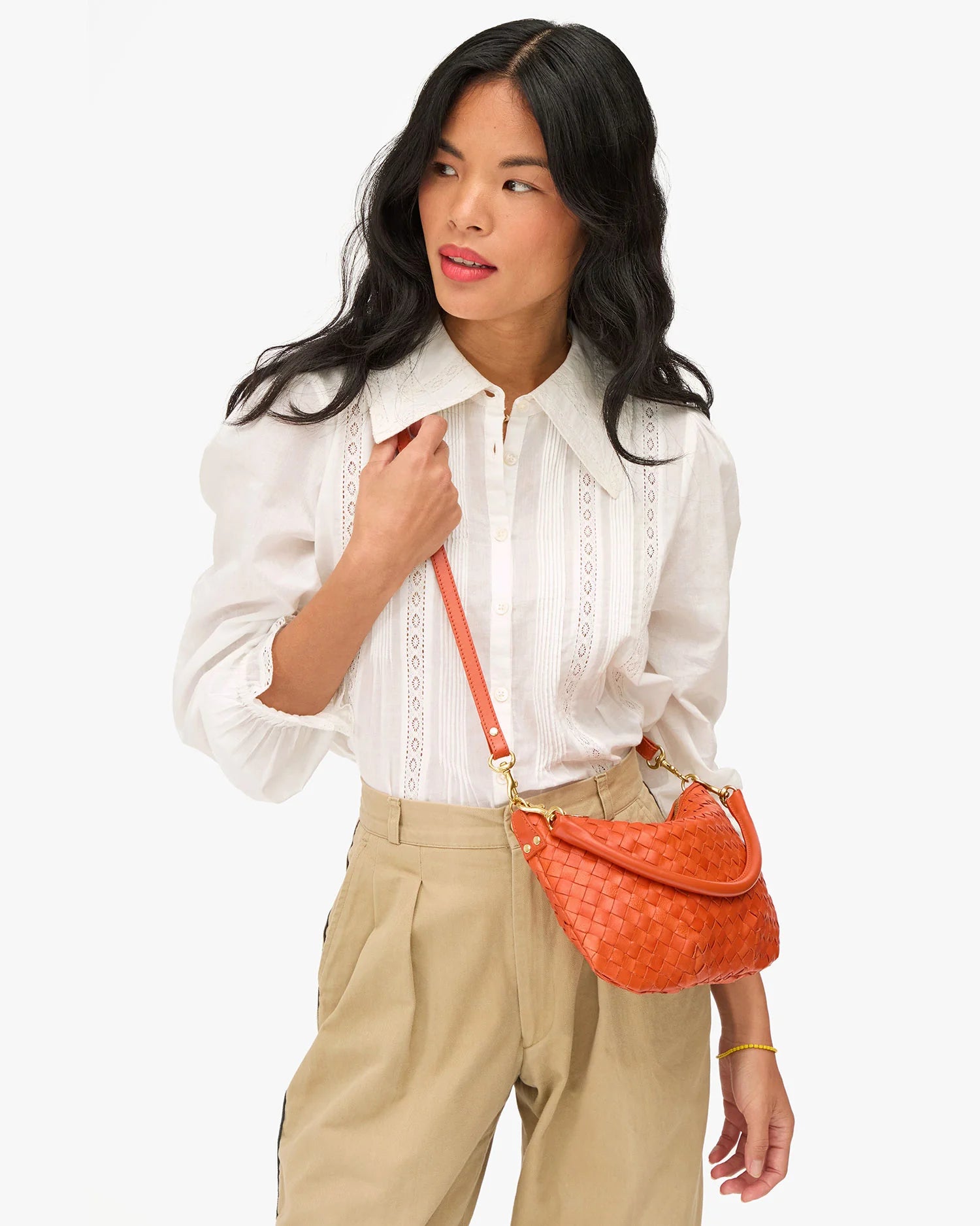 Woman holding an orange handbag against a white background