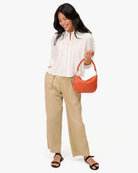 Woman holding an orange handbag against a white background