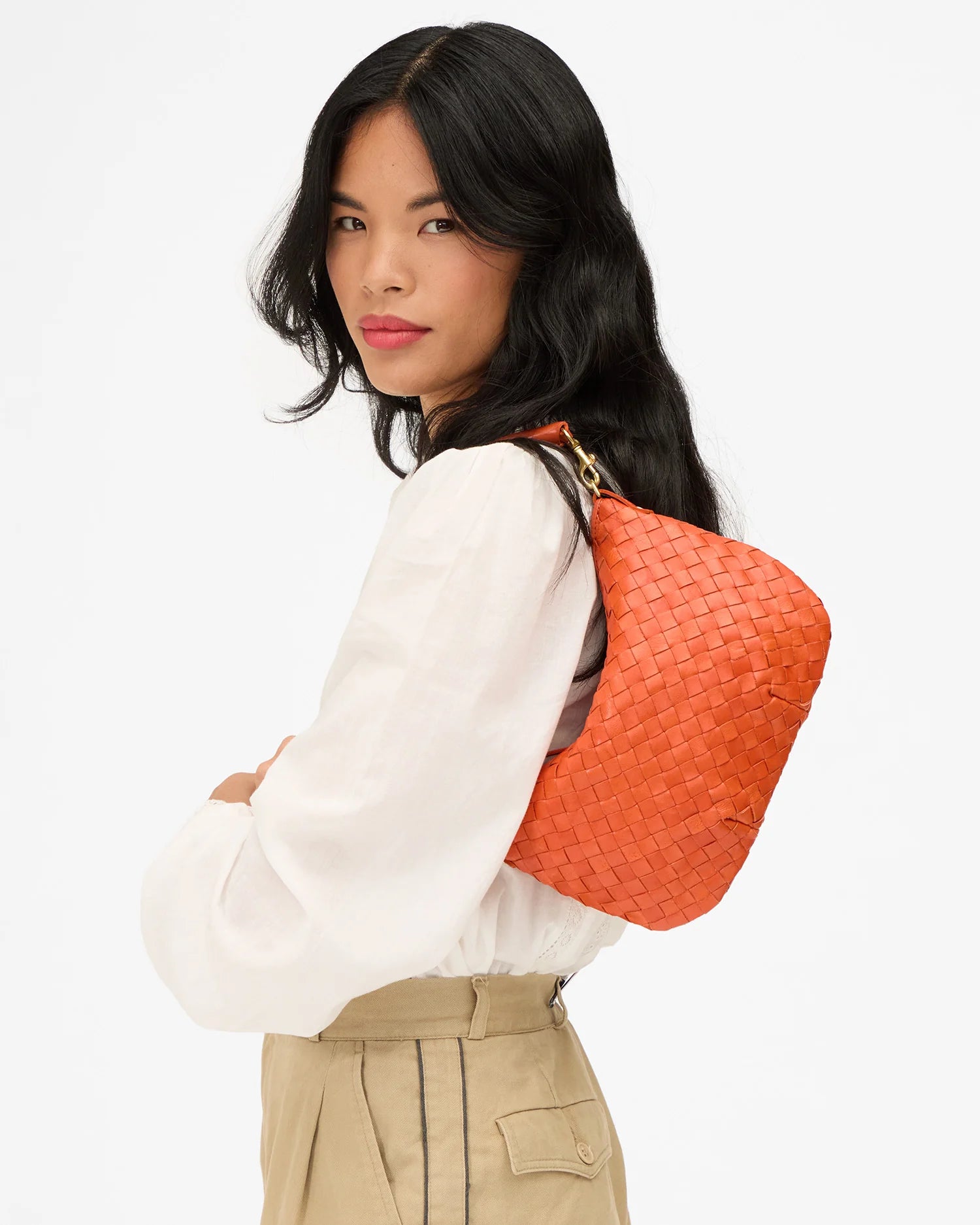 Woman carrying an orange woven handbag on a white background