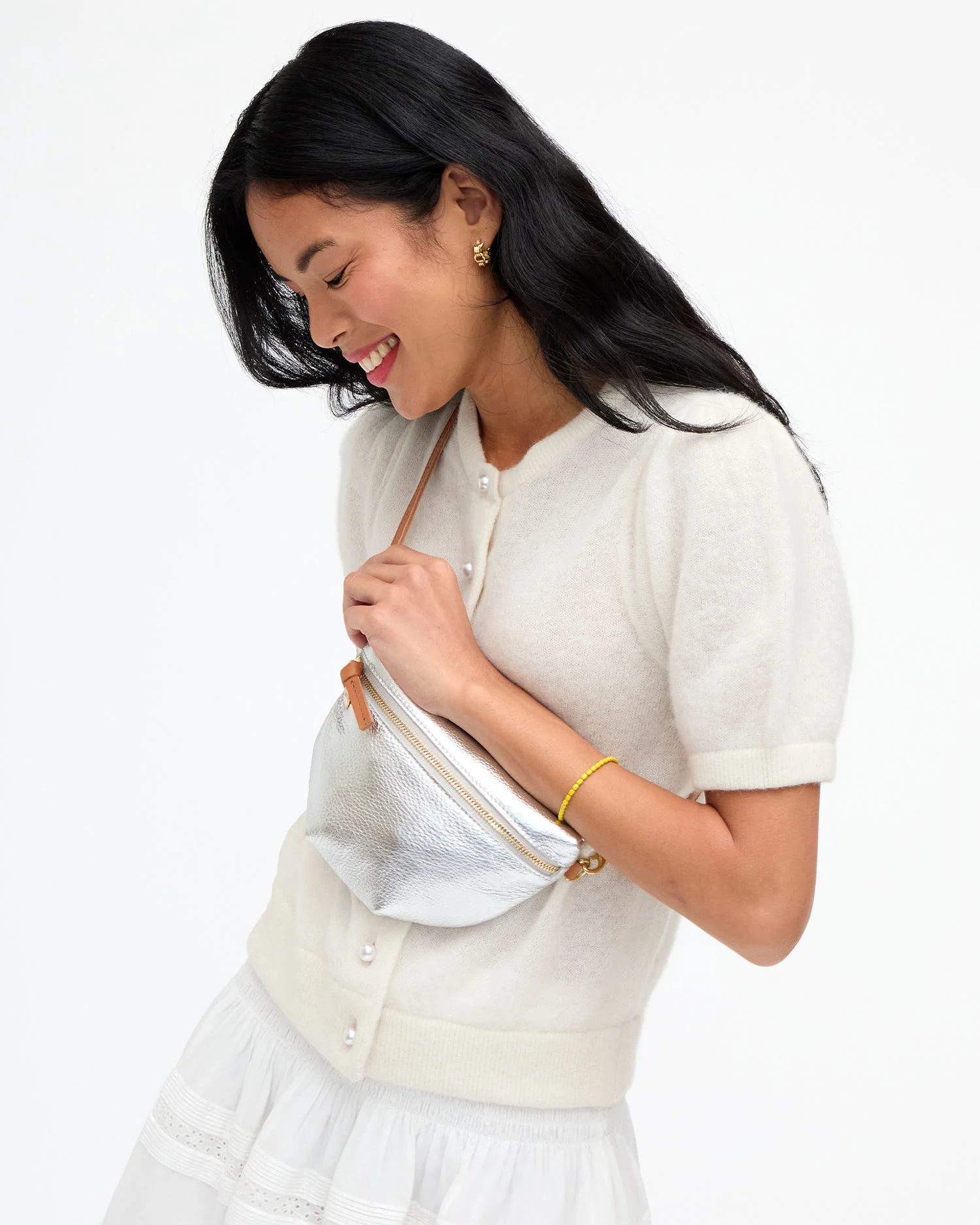 Woman wearing a white outfit with a matching handbag on a white background