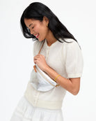 Woman wearing a white outfit with a matching handbag on a white background