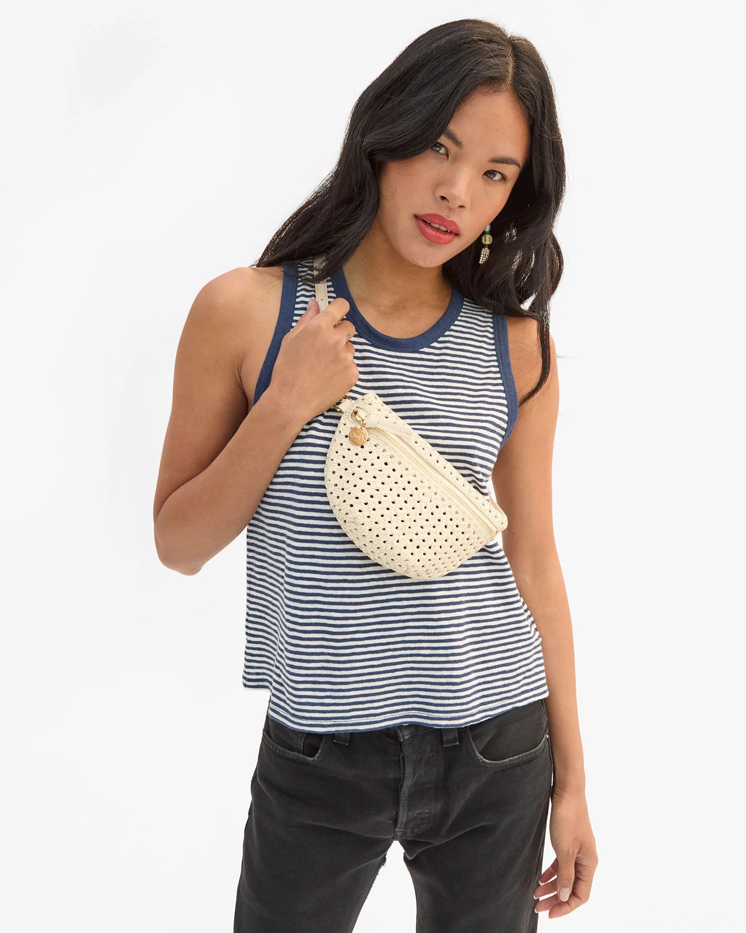 Woman holding a white woven handbag against a plain background