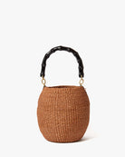 Brown woven handbag with black bamboo handle on a white background