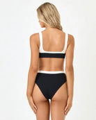 Woman wearing a black and white bikini on a white background