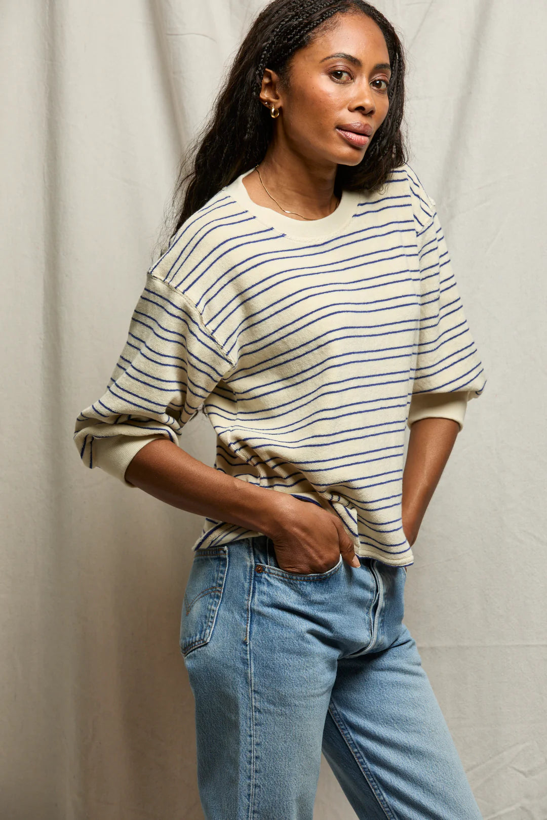 Woman wearing a striped sweater and jeans against a plain background