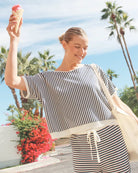Woman in a striped outfit holding an ice cream cone with palm trees and flowers in the background
