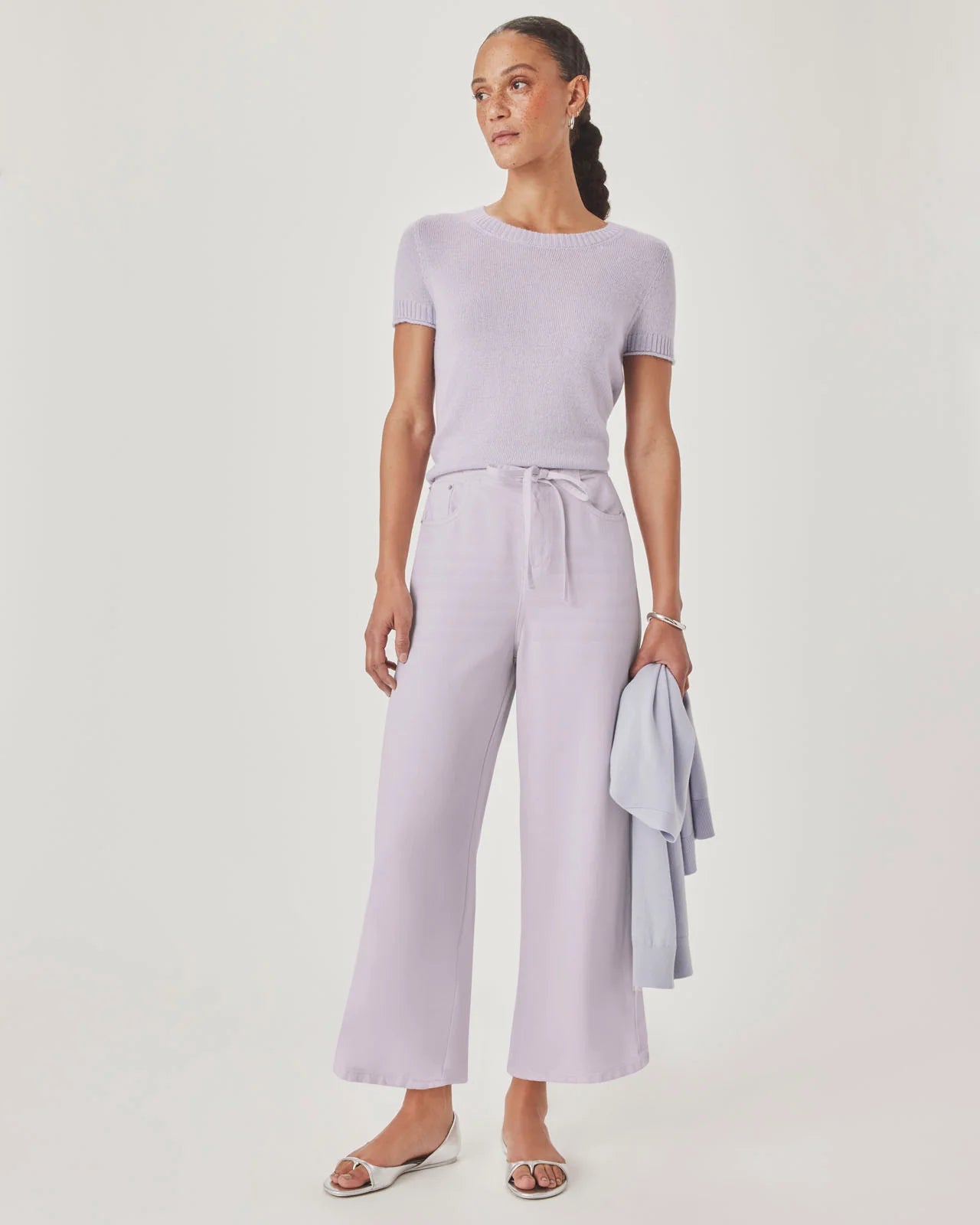 Woman wearing a light purple outfit with wide-leg pants and a matching top on a white background
