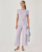 Woman wearing a light purple outfit with wide-leg pants and a matching top on a white background