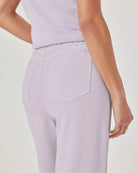 Person wearing light purple pants and a matching top on a plain background