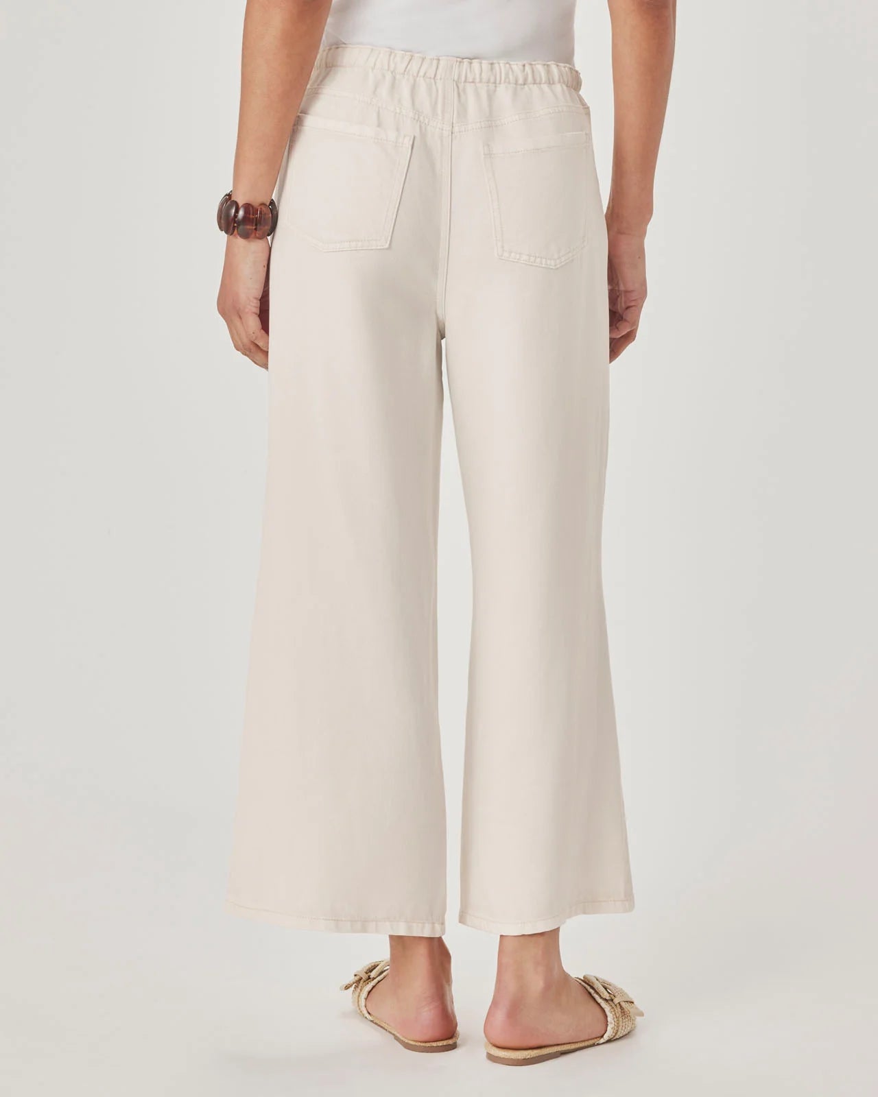 Person wearing beige wide-leg pants on a plain background