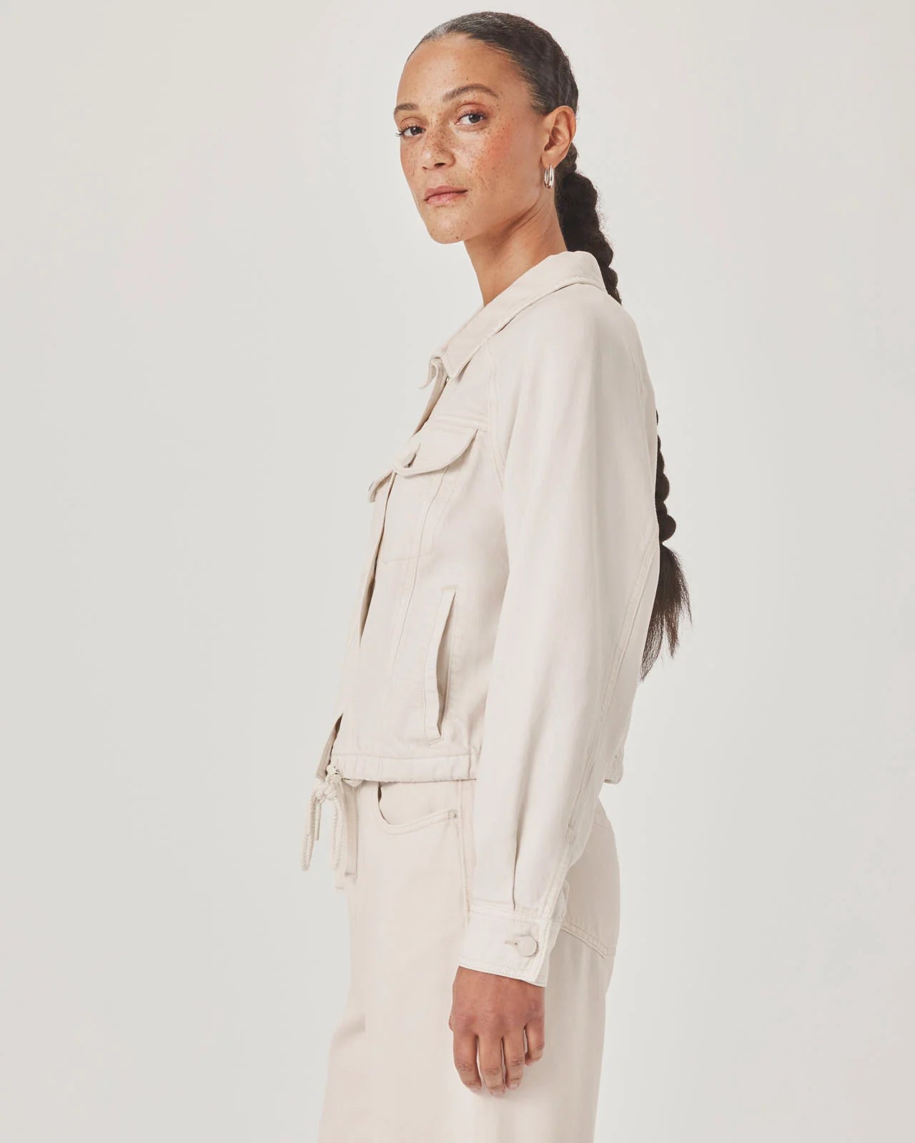 Woman wearing a beige jacket and pants against a white background