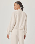 Woman wearing a beige jacket and pants on a plain background