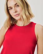 Woman wearing a red sleeveless top against a plain background