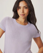 Woman wearing a light purple short-sleeve sweater against a plain background