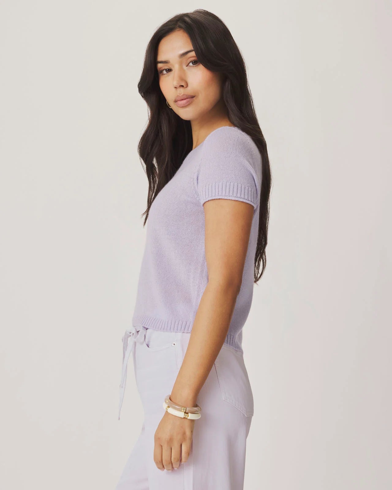 Woman wearing a light purple sweater and pants against a plain background