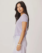 Woman wearing a light purple sweater and pants against a plain background