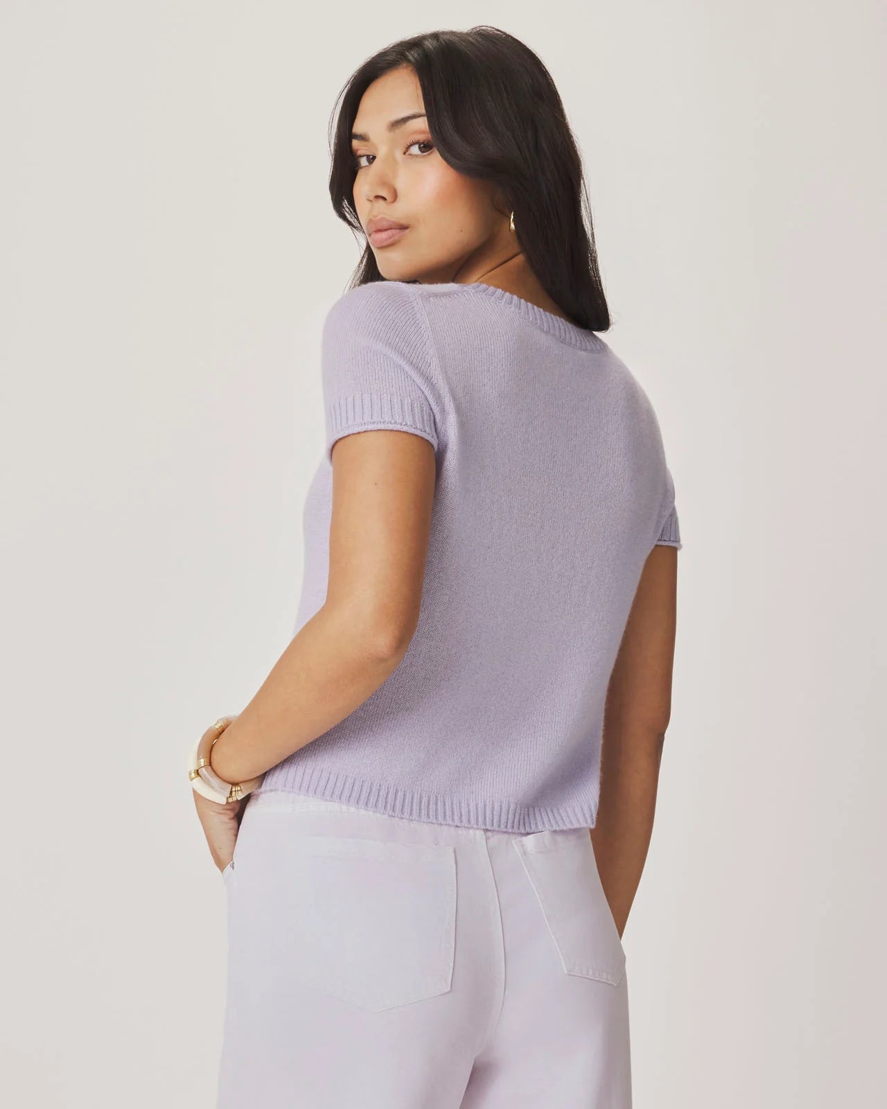 Woman wearing a light purple sweater and pants against a plain background