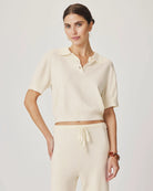 Woman wearing a cream-colored outfit with a matching top and pants on a plain background