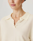 Close-up of a person wearing a light-colored shirt with a plain background