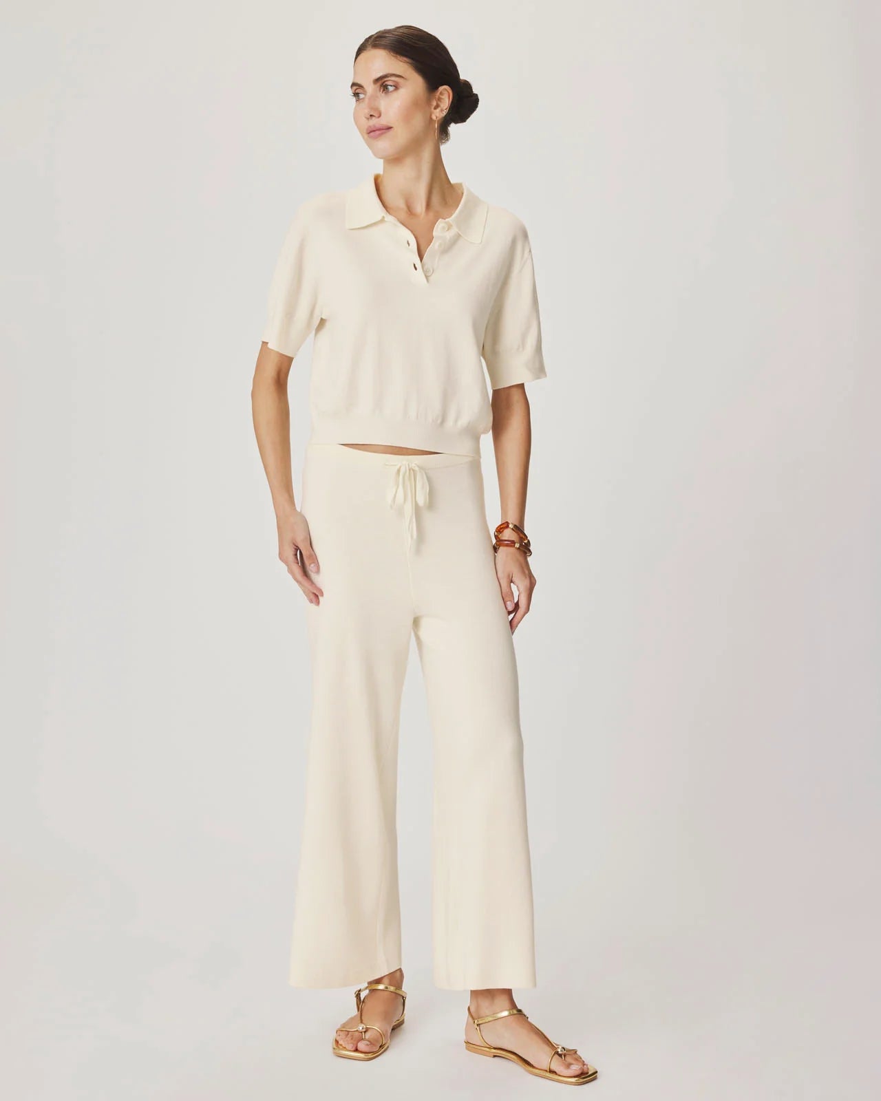 Woman wearing a cream-colored outfit with a plain background