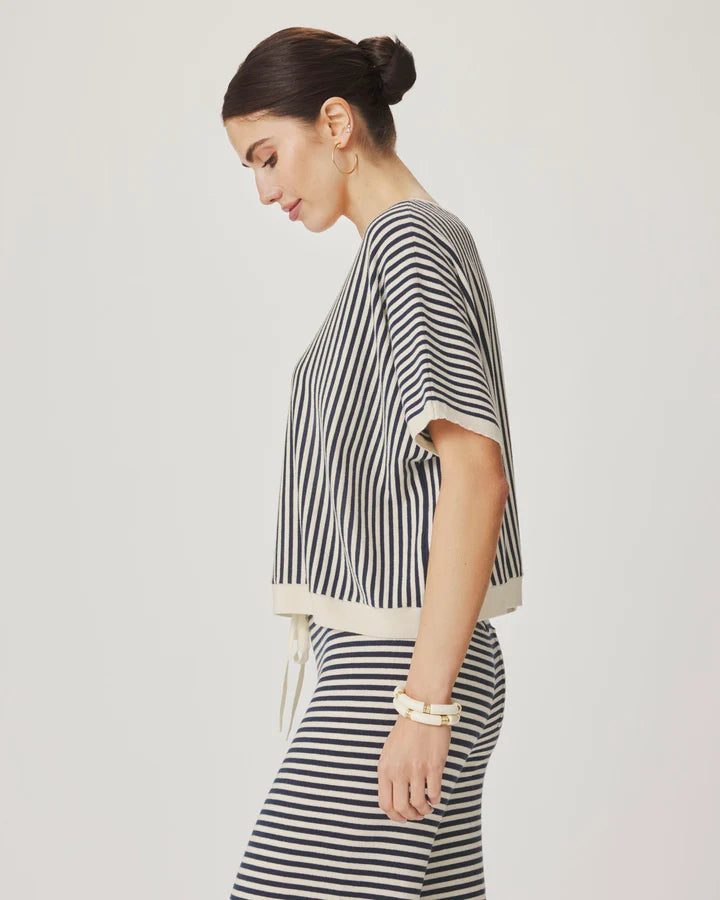 Woman wearing a black and white striped outfit on a plain background