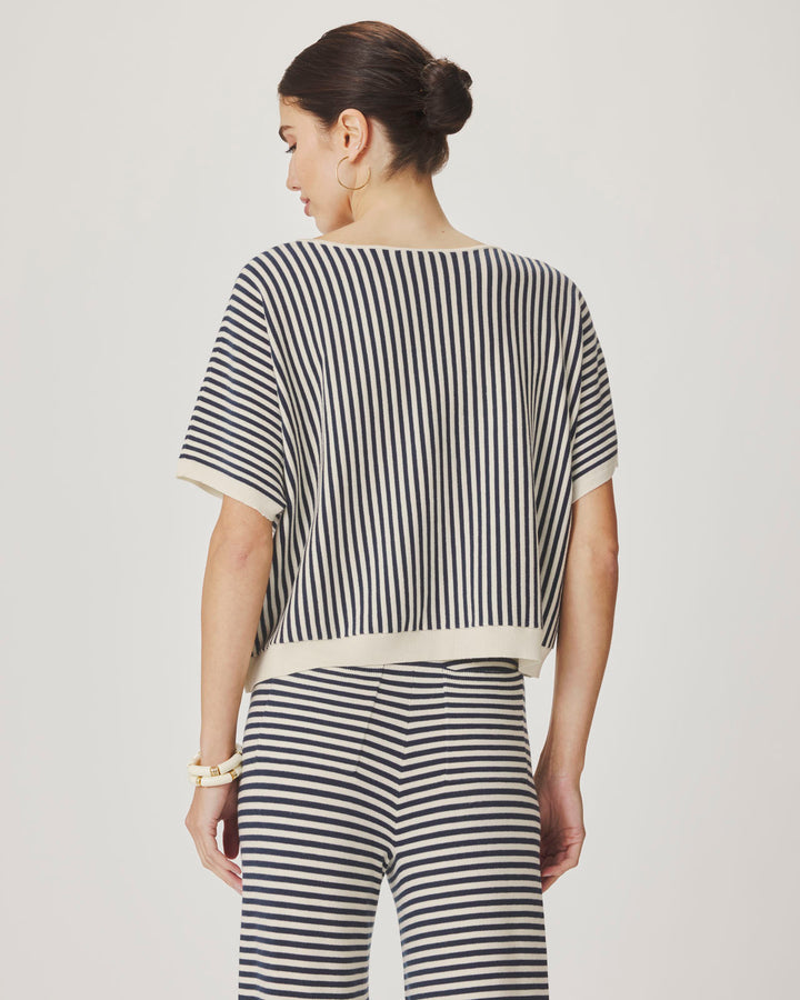 Woman wearing a black and white striped outfit on a plain background