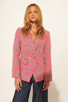 Woman wearing a red and white checkered blazer against a plain background