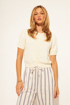 Woman wearing a white blouse and striped pants against a plain background
