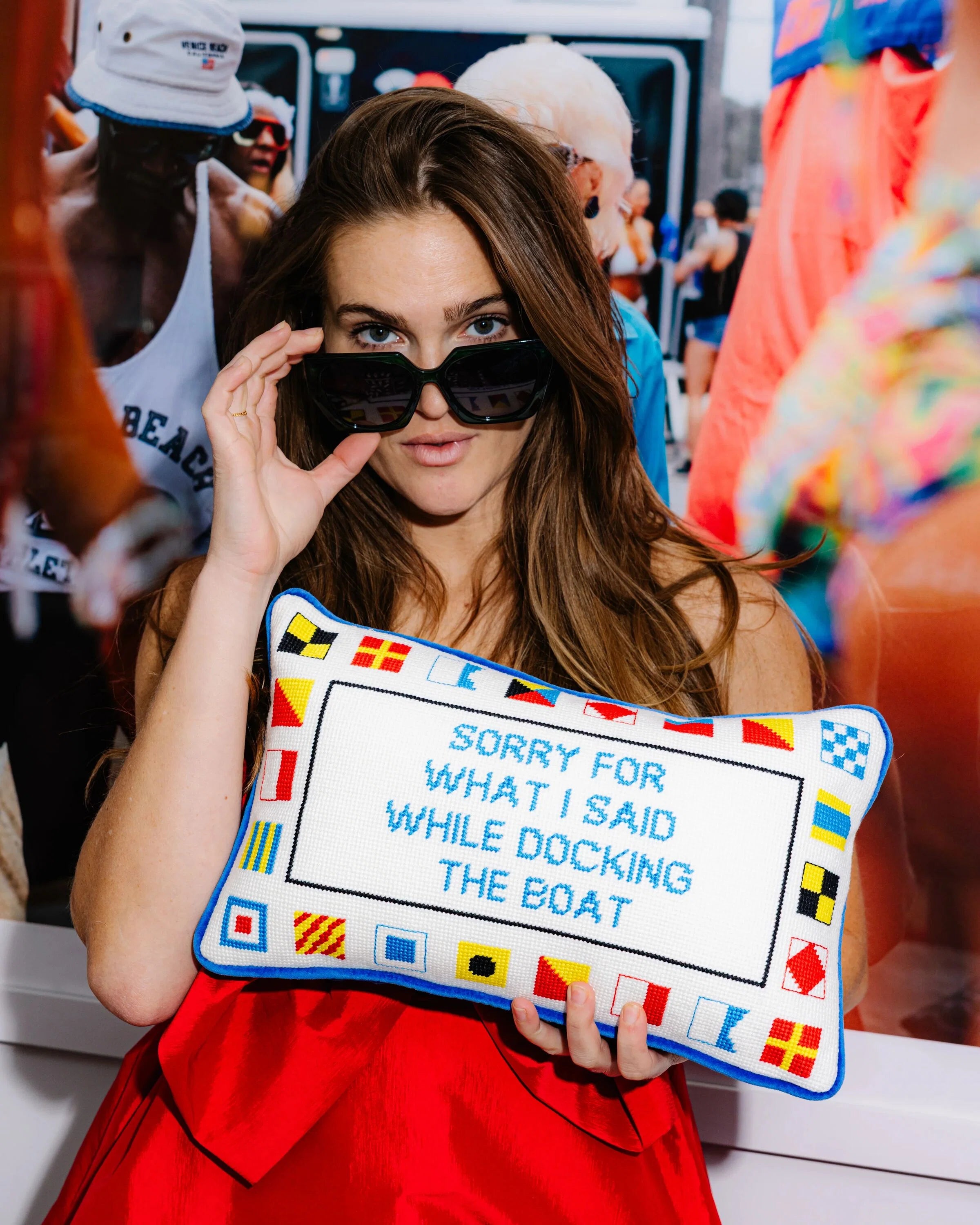 Woman holding a pillow with text and colorful border in a casual setting