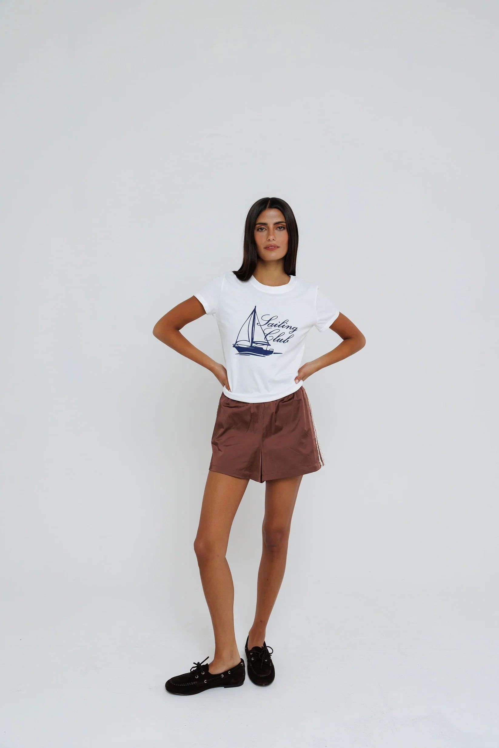 Woman wearing a white t-shirt with a graphic design on a plain background